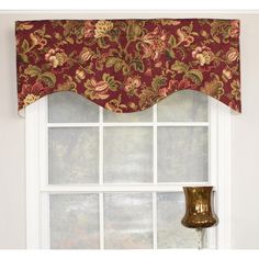 a window with a red flowered valance hanging from it's side next to a lamp