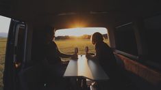 two people sitting at a table in the back of a van on a sunny day