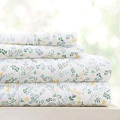 the sheets are stacked on top of each other in front of a window with green and yellow flowers