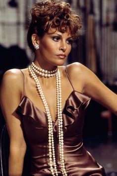 a woman in a brown dress with pearls on her neck