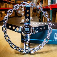 a metal steering wheel on top of a wooden table next to a box and chain