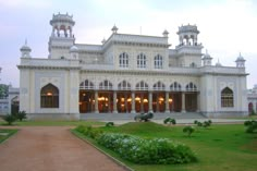 a large white building with lots of windows on it's sides and green grass in front