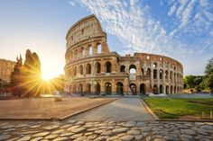 the roman colossion in rome, italy at sunset with sun shining through clouds