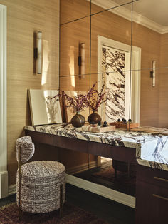 a mirror sitting on top of a wooden desk next to a chair and table with vases