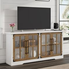 an entertainment center with a flat screen tv mounted on it's side, in front of a window