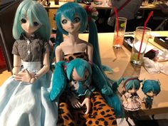 three dolls sitting on top of a table next to each other