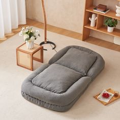 a grey couch sitting on top of a white floor next to a table with flowers