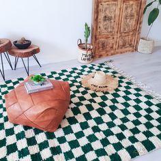 a green and white rug sitting on top of a wooden floor next to two stools