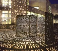 the words are projected on the ground in front of a tall building at night time