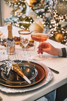 a person holding a wine glass in front of a table set with champagne and crackers