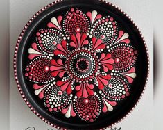 a red and black plate with white dots on it's rim, decorated with an intricate flower design