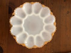 a white and gold plate sitting on top of a wooden table