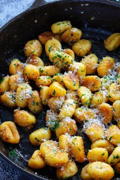 a skillet filled with potatoes covered in parmesan cheese