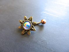 a gold colored brooch with an opal in the center on a gray surface