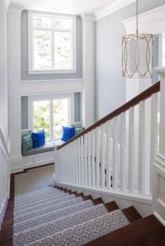 the stairs in this house are painted white and have blue pillows on them, along with a window seat