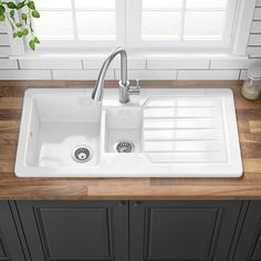 a white kitchen sink sitting on top of a wooden counter