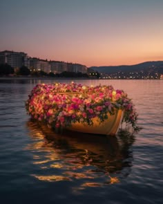 a boat filled with lots of flowers floating on top of a body of water at sunset