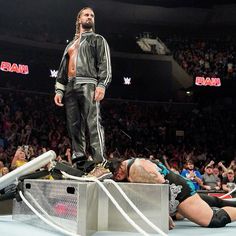 a man standing on top of a wrestling ring next to another person laying on the ground