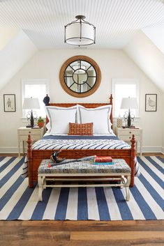 a bedroom with white walls and blue striped rugs on the floor, along with a large bed