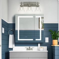 a bathroom with blue and white walls, two lights on the vanity and a large mirror over the sink