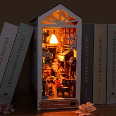 an open doll house sitting on top of a wooden table next to books and flowers