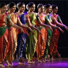 a group of women standing on top of a stage holding hands in each other's pockets