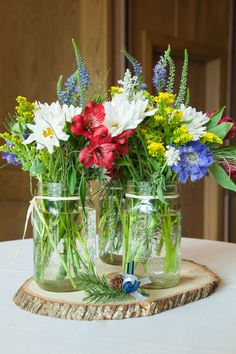 three mason jars filled with flowers on top of a table