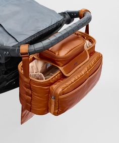 an open brown leather bag sitting on top of a white table next to another bag