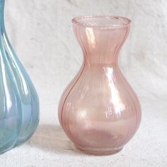 two glass vases sitting next to each other on a white surface