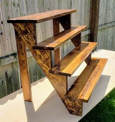 a wooden shelf sitting on top of a white table in front of a wood fence