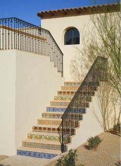 an outdoor stair case with decorative tiles and wrought iron railing