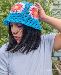 a woman wearing a blue crocheted hat with flowers on it