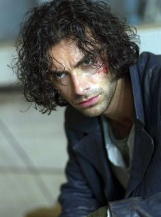 a man with curly hair sitting on the ground