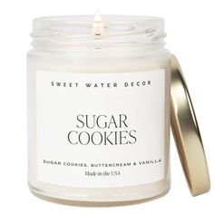 a jar of sugar cookies sitting on top of a white table next to a candle