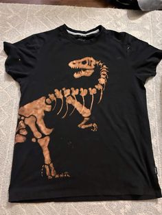 a black t - shirt with a dinosaur skeleton on it's chest and feet