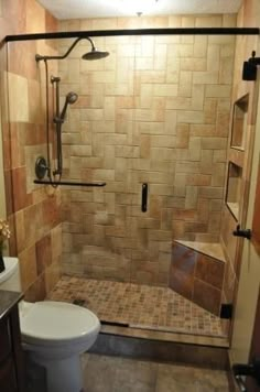 a bathroom with a toilet, shower and tiled walls