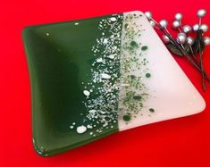 a green and white plate sitting on top of a red table next to silver balls