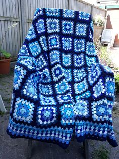 a blue crocheted blanket sitting on top of a chair