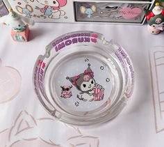 a hello kitty glass ashtray sitting on top of a table next to other items