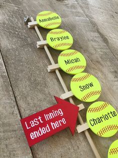 a row of yellow baseballs sitting on top of a wooden floor next to a red arrow