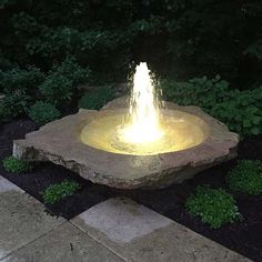 a stone fountain in the middle of a garden