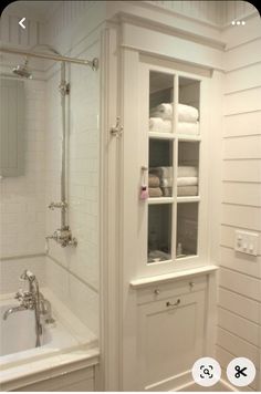 a bathroom with white walls and cabinets in the corner, along with a bathtub