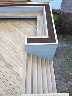 a wooden deck with two planters on the top and one in the bottom corner