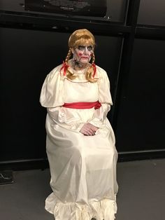 a woman dressed in white and red sitting on a chair with her hands behind her back