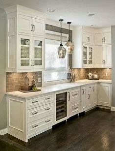 a kitchen filled with lots of white cabinets and counter top space next to a window