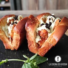 two pieces of bread with cheese and black olives on it sitting on a table