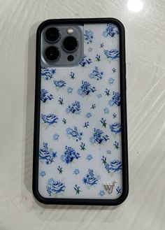 an iphone case with blue flowers on it sitting on top of a white countertop