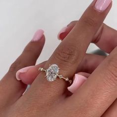 a woman's hand holding a ring with a diamond on it and the other hand