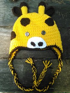 a crocheted hat with a cow's head on it sitting on top of a piece of wood