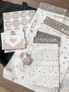 some papers and stickers sitting on top of a wooden table next to a black bag